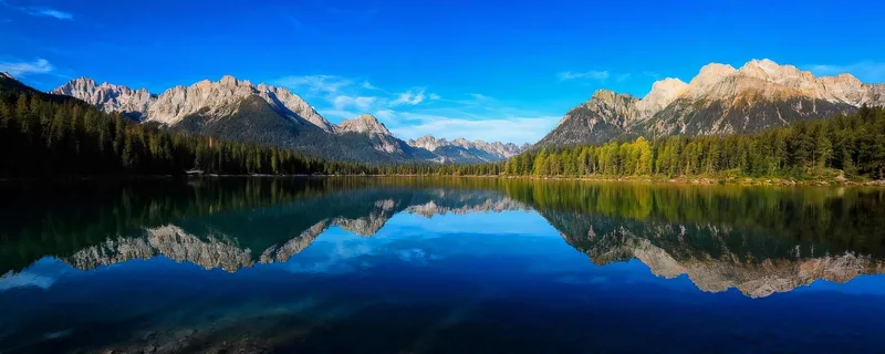 Pintura De Montañas El Lago De Braies Con Aguas Cristalinas Y Espectaculares Picos Montañosos